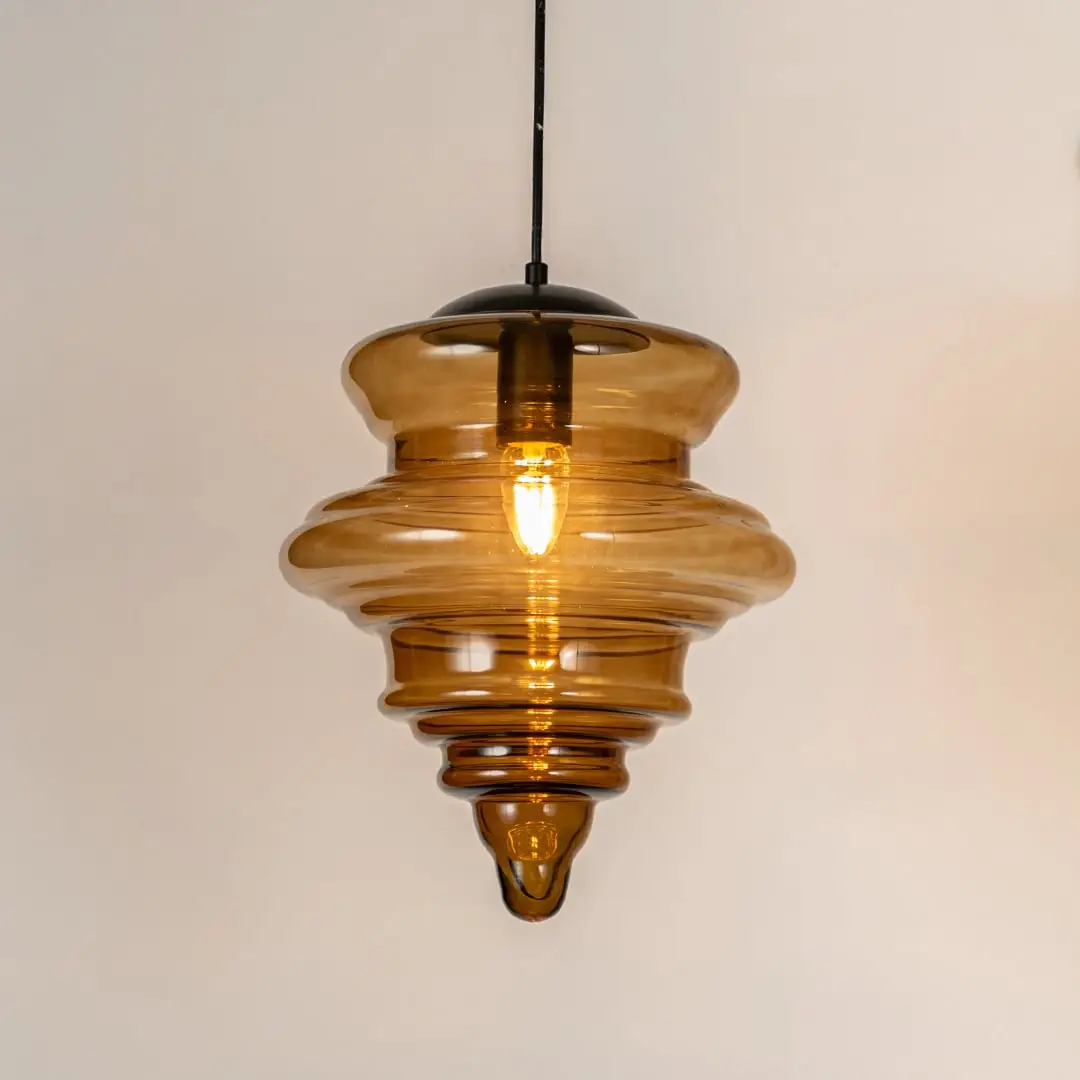 Amber ribbed glass pendant light with layered glass design and exposed bulb for warm modern ceiling lighting.