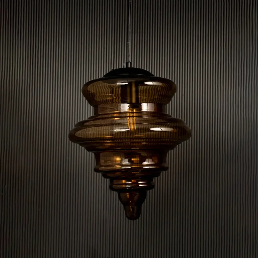 Amber glass pendant light displayed on dark background with lights off highlighting its glossy texture and sculptural design.