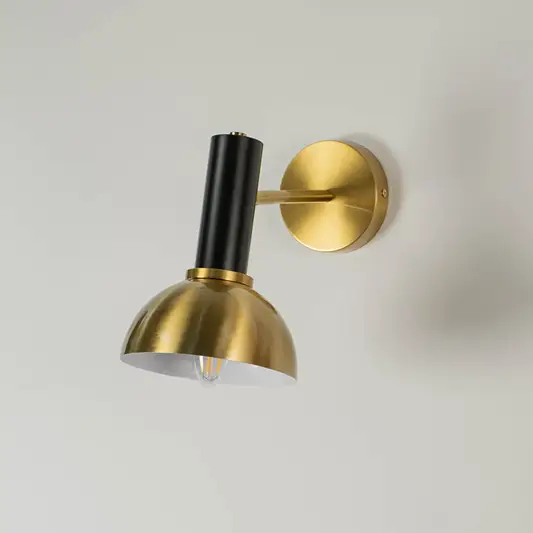 Gold and black wall light displayed without illumination against a white background showcasing its sleek dome design and elegant finish.