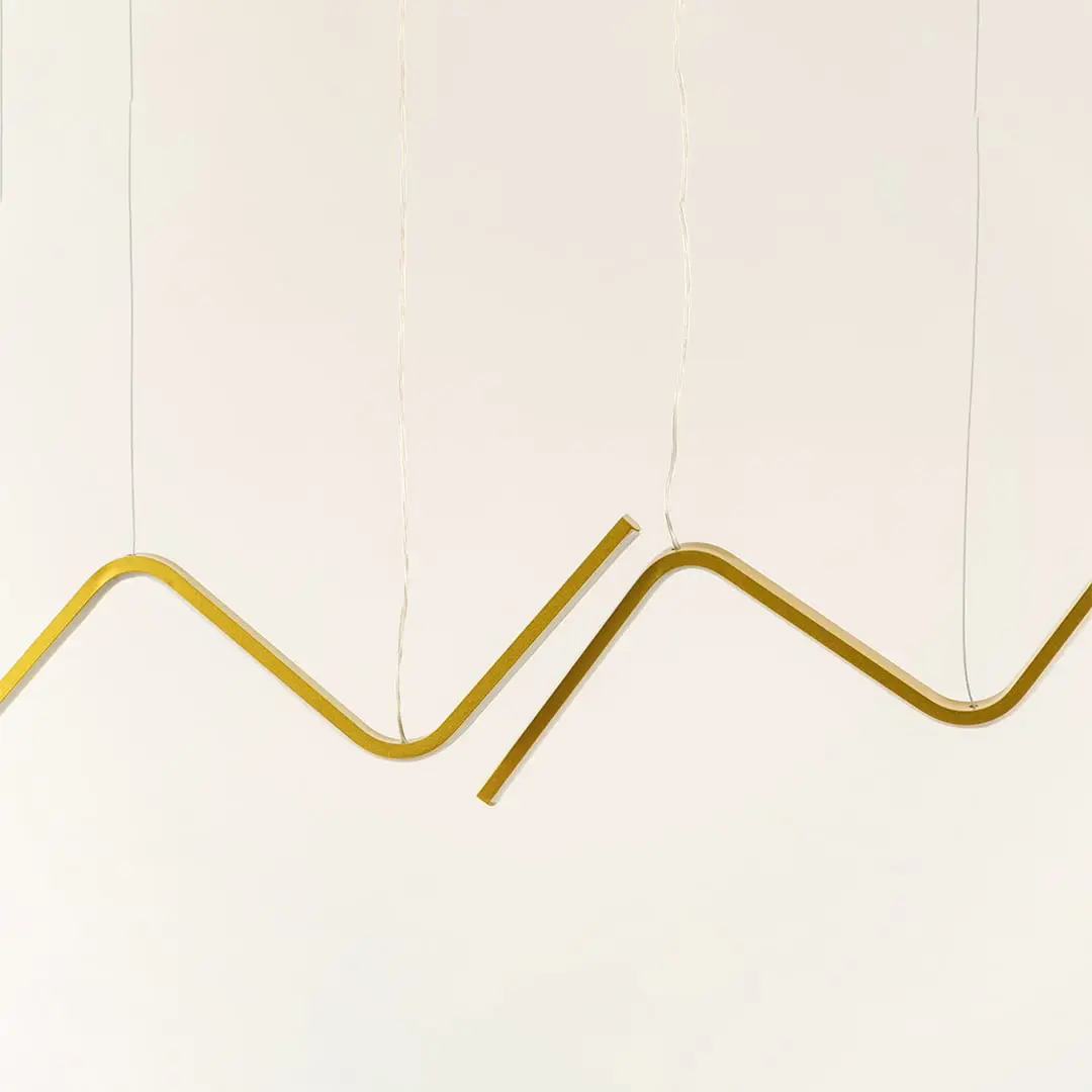 Gold sculptural chandelier featuring sweeping wave shaped LED bars suspended elegantly creating a warm dynamic decorative lighting accent in the modern room.