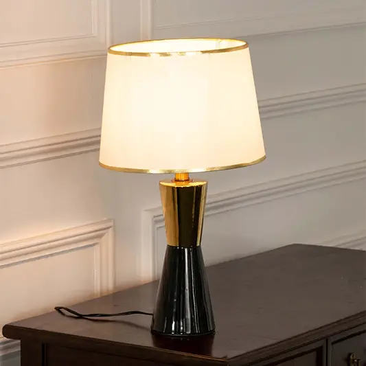 Black ceramic table lamp with fabric shade and gold accents creating sophisticated modern ambient lighting for interiors.