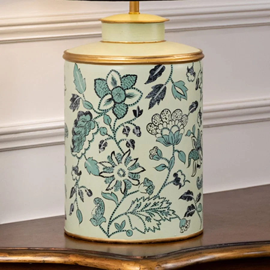 Table lamp closeup displaying floral motif on ceramic base with teal shades intricate detailing and glossy surface.