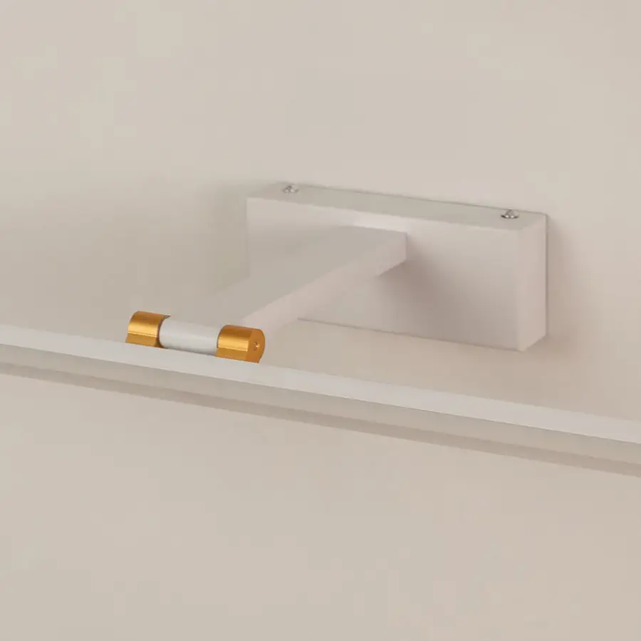 Closeup of white and gold metal picture light showing slim bar design smooth finish and warm directional illumination.