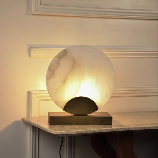Artistic marble effect table lamp with glowing sculptural shade providing soft ambient light for luxury interiors.