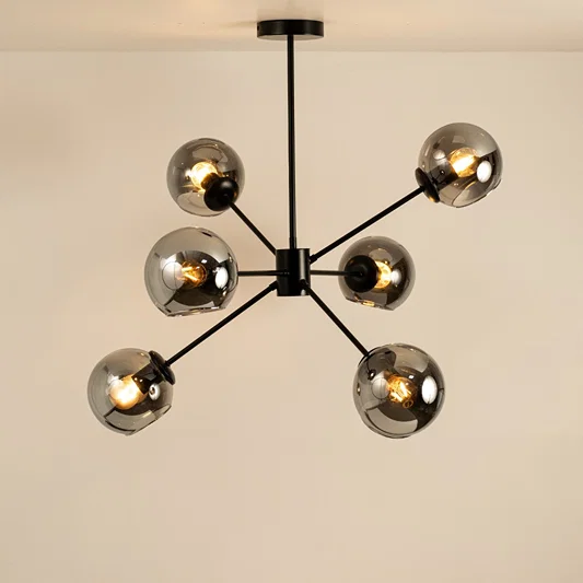 Black and gold metal chandelier with illuminated exposed bulbs creating warm ambient lighting for stylish interiors.