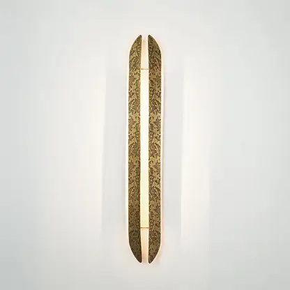 Gold wall light with elongated textured metal design mounted on neutral wall background ideal for modern luxury interior decor lighting.