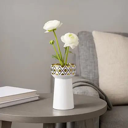 A modern white decorative vase with gold detailing styled on a clean surface creating an elegant lifestyle look for contemporary home decor.