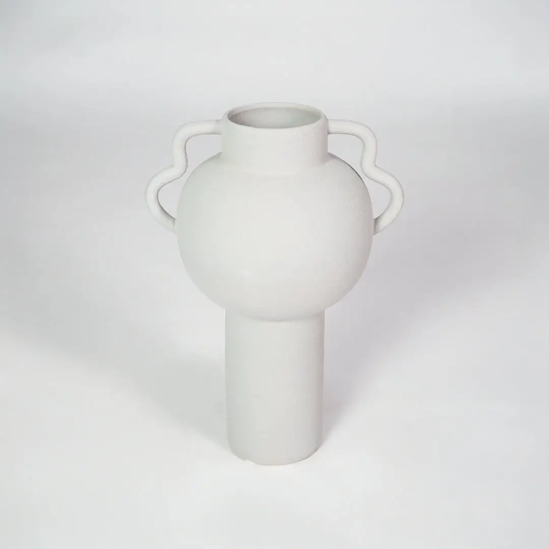 White ceramic vase with side handles for modern shelf placement and elegant indoor home decor styling accent.