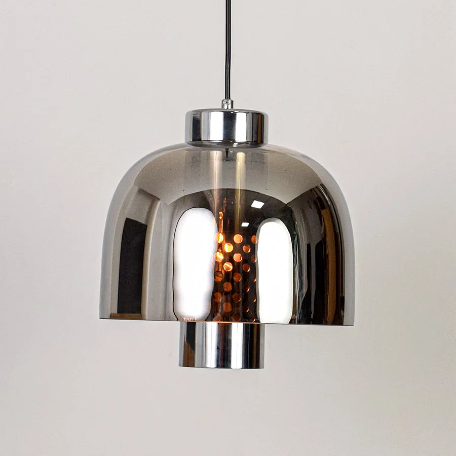 Smoke glass and chrome metal pendant light designed for modern dining room and home decor spaces.