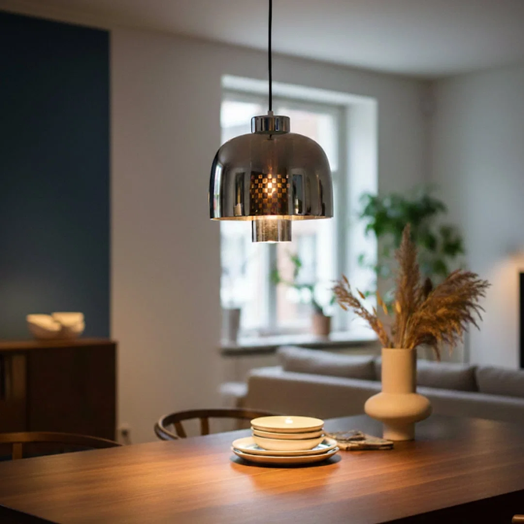 Smoke glass and chrome metal pendant light creating elegant ambience in contemporary dining interiors.