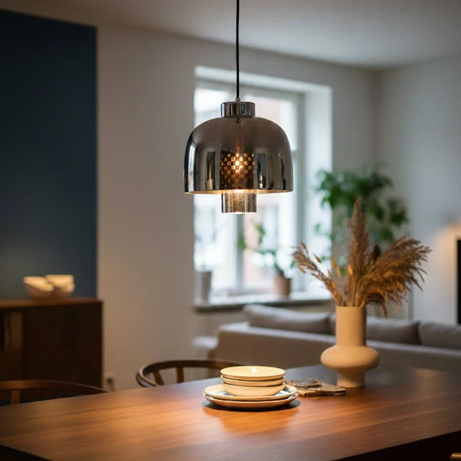 Smoke glass and chrome metal pendant light creating elegant ambience in contemporary dining interiors.