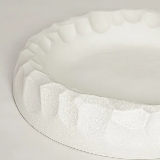 White ceramic decorative bowl with sculpted textured rim perfect for elegant dining table centerpiece and interior decor styling.