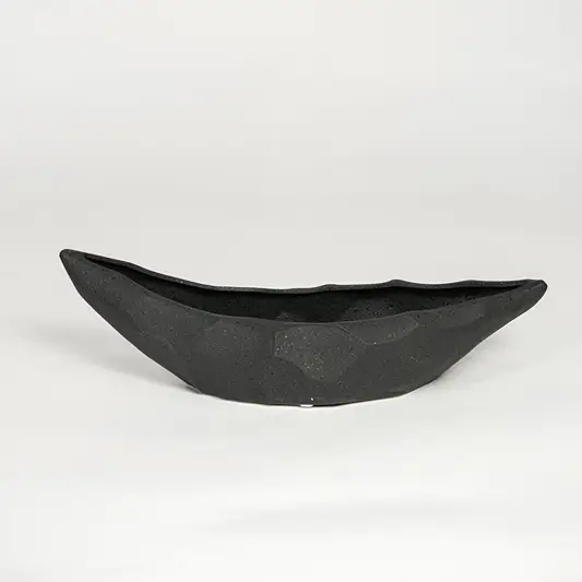 Black ceramic decorative platter with angular faceted texture isolated on clean white background for modern table decor styling.
