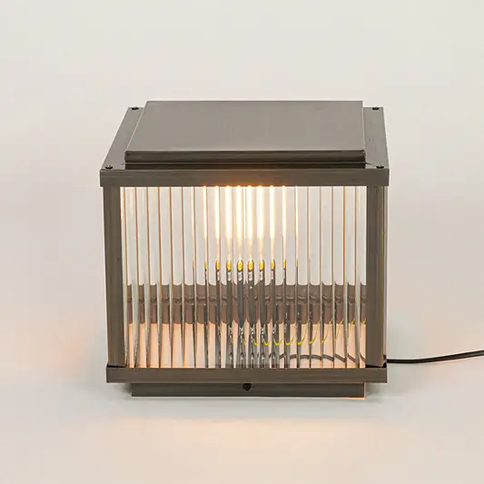 Modern outdoor wall or pillar light with ribbed glass and metal frame on neutral background creating warm ambient exterior lighting.