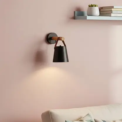 Contemporary black metal spotlight wall light enhancing cozy bedroom ambiance with warm lighting.
