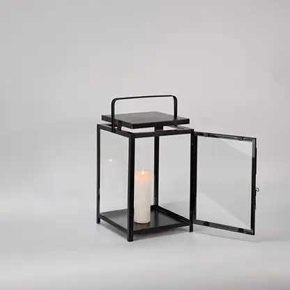 Black metal lantern with open glass door and candle holder for elegant indoor decor styling.