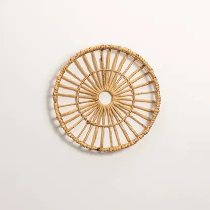 Round handcrafted natural rattan open center web wall basket wheel panel on white background for boho home wall decor display.
