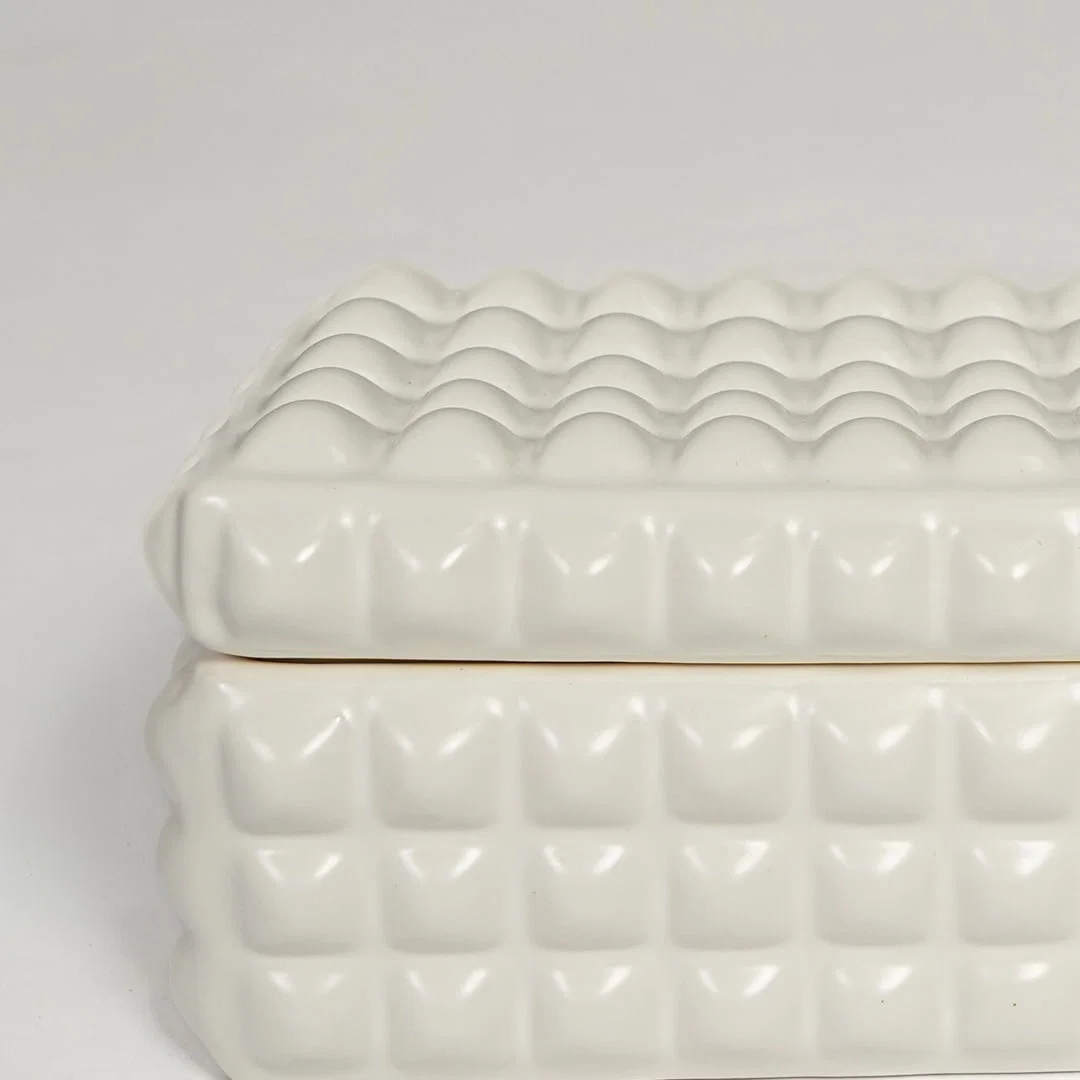 Detailed closeup of white ceramic storage box showcasing raised geometric texture and glossy finish.