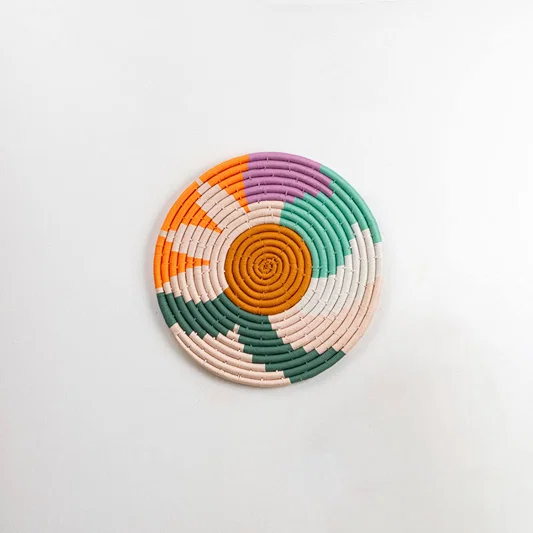 Natural woven multicolor seagrass wall basket with orange green cream and pink pattern on white background image.