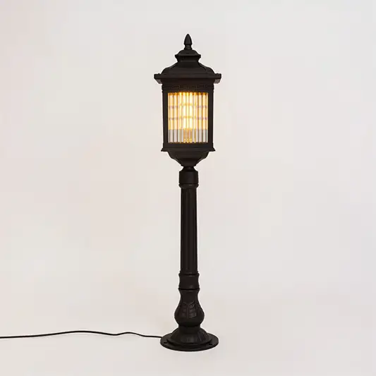 Vintage black outdoor bollard light with warm glowing panels for luxury exterior decor styling use.