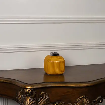 Yellow ribbed ceramic mini vase displayed on a clean white background highlighting its glossy top and modern shape.