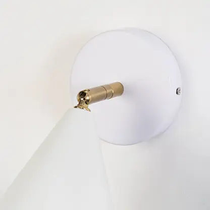 Closeup view of white metal wall sconce highlighting its conical shade smooth matte finish and warm lighting design suited for modern interior decor.
