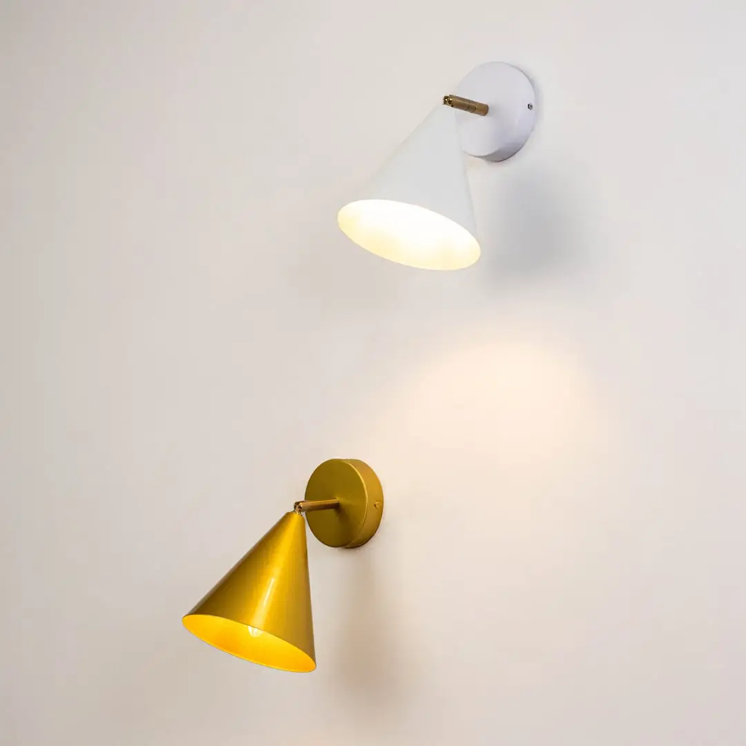 White and gold conical wall sconces glowing warmly together on a light background creating a stylish modern accent lighting look for interior home decor.