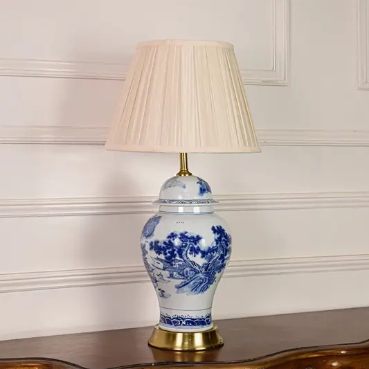 Blue and white ceramic table lamp shown unlit on white background featuring pleated fabric shade and classic porcelain base.