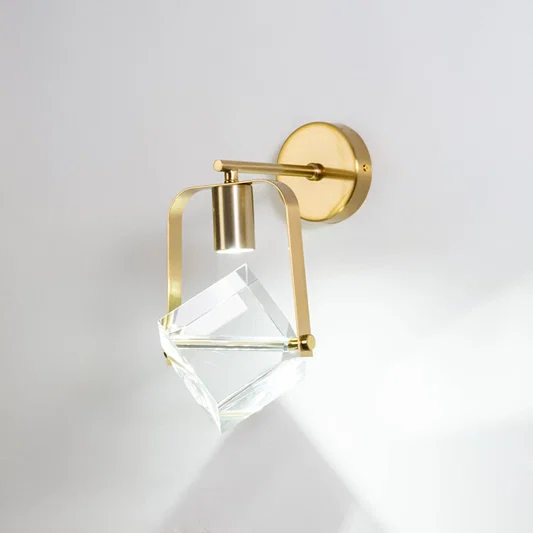 Gold metal crystal wall light on white background with geometric glass shade for luxury modern wall decor.