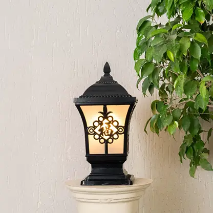 Black metal outdoor post lantern Light On mounted on a stone pillar Traditional garden gate lighting Main Lifestyle image at night.