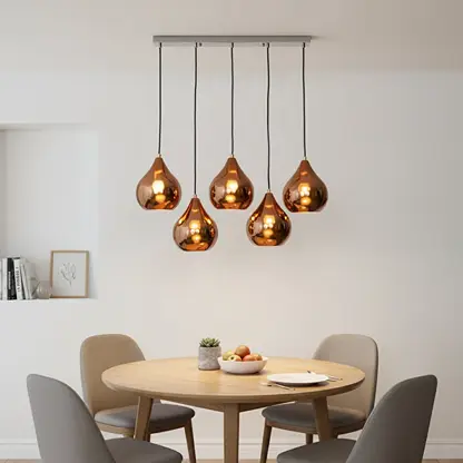 Amber metallic glass pendant lights creating cozy ambience above the dining table in elegant interiors.