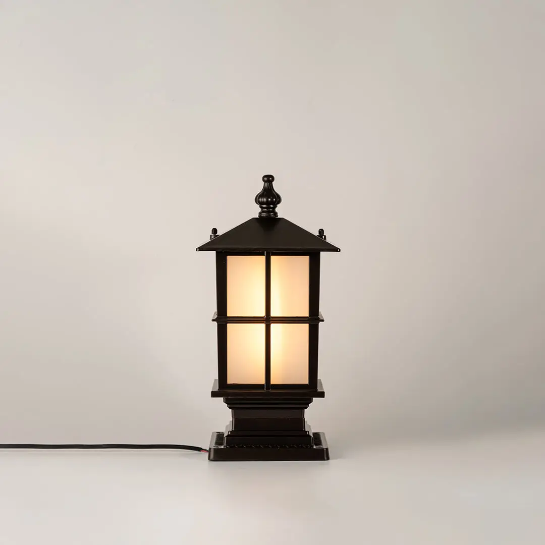 Vintage black outdoor gate light with warm glowing glass panels for elegant exterior decor use.