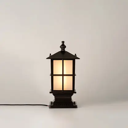 Vintage black outdoor gate light with warm glowing glass panels for elegant exterior decor use.