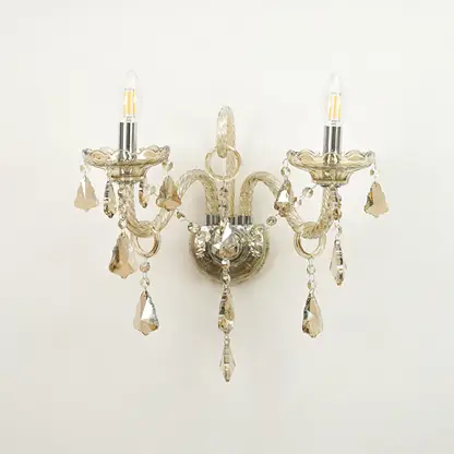 A double-arm wall sconce with a distressed silver metal finish, featuring clear glass candle-style bulbs and hanging faceted crystal drops against a plain white background.
