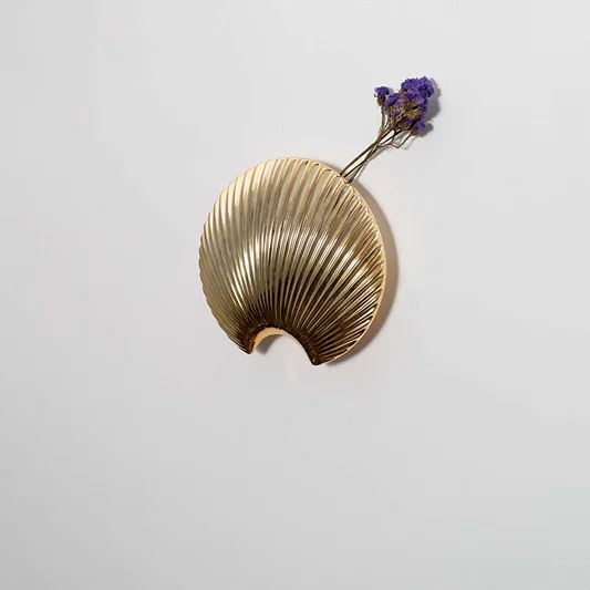 Gold finish metal leaf wall hook styled on a modern wall for bedroom entryway or living room decor and storage.