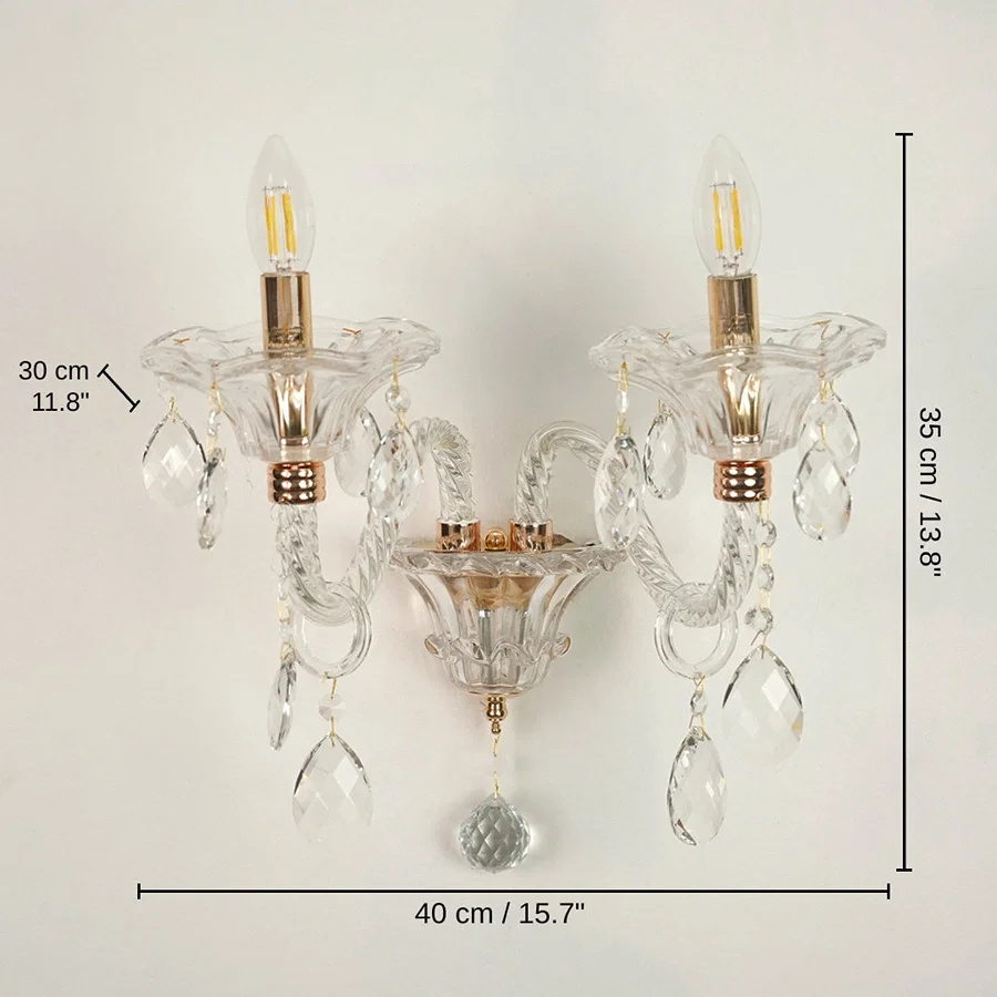 Two-light wall sconce with clear glass crystal prisms and gold-finished metal accents, 35 x 40 x 30 cm (13.8 x 15.7 x 11.8 inches) dimensions