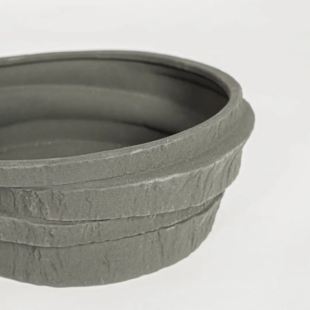 Black ceramic serving bowl with rustic textured stone finish perfect for elegant dining table centerpiece and contemporary home decor styling.