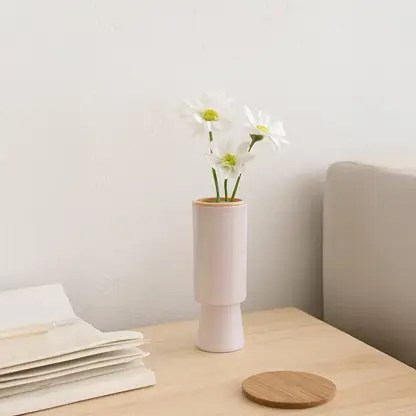Modern blush ceramic vase displayed in a soft minimal setting showing its tall cylindrical shape and elegant matte finish.
