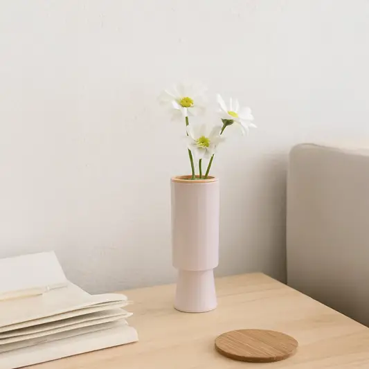 Modern blush ceramic vase displayed in a soft minimal setting showing its tall cylindrical shape and elegant matte finish.