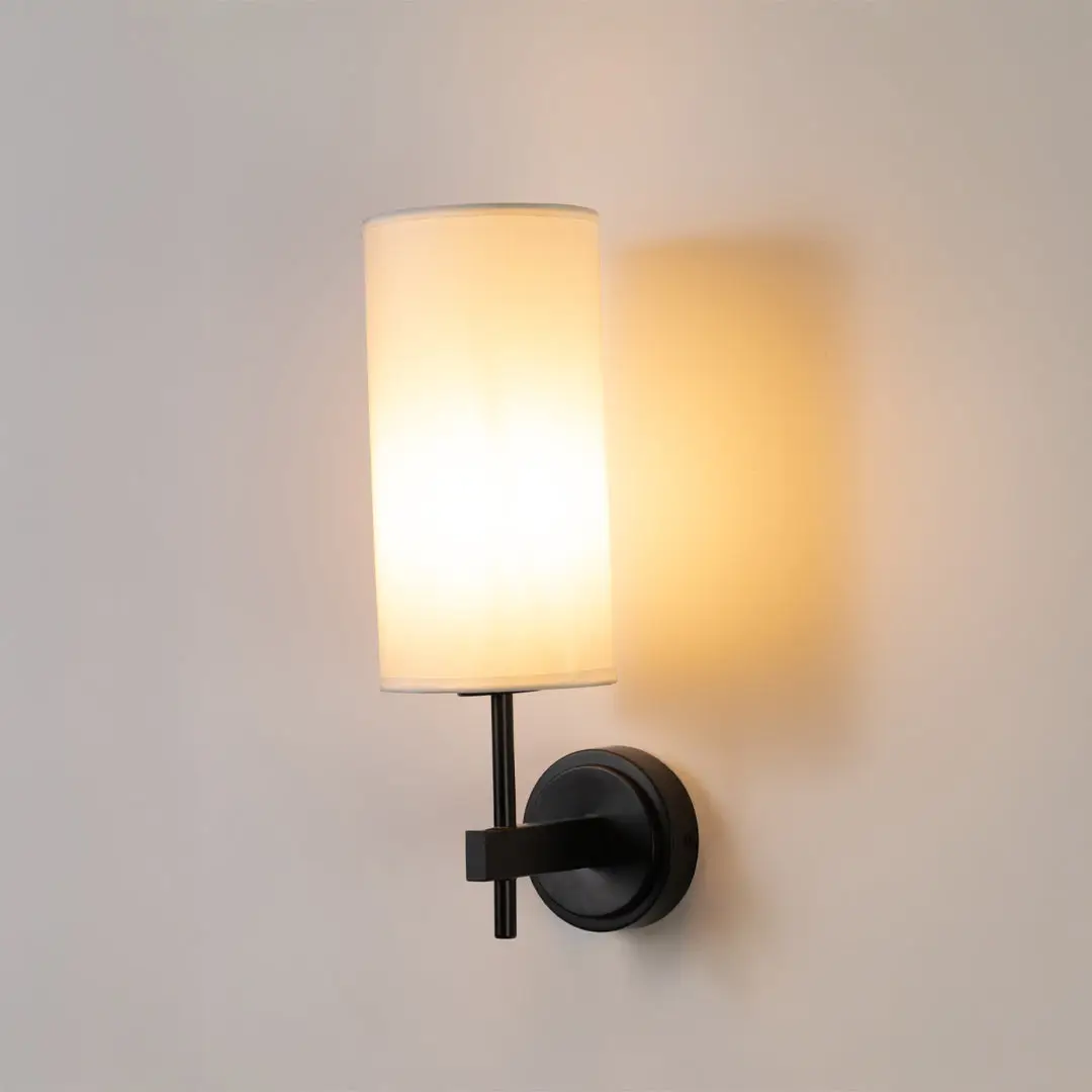 Contemporary wall light in black metal finish with fabric shade for bedroom or living decor lighting white background.