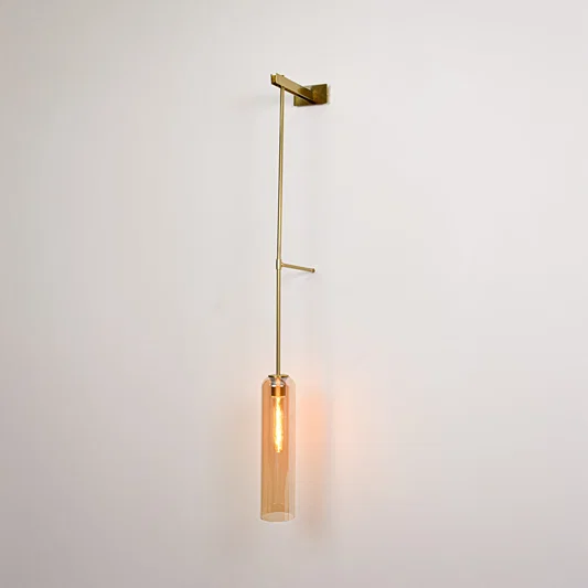 Gold metal wall light with hanging tube shade emitting warm ambient glow ideal for bedroom or hallway wall decor.