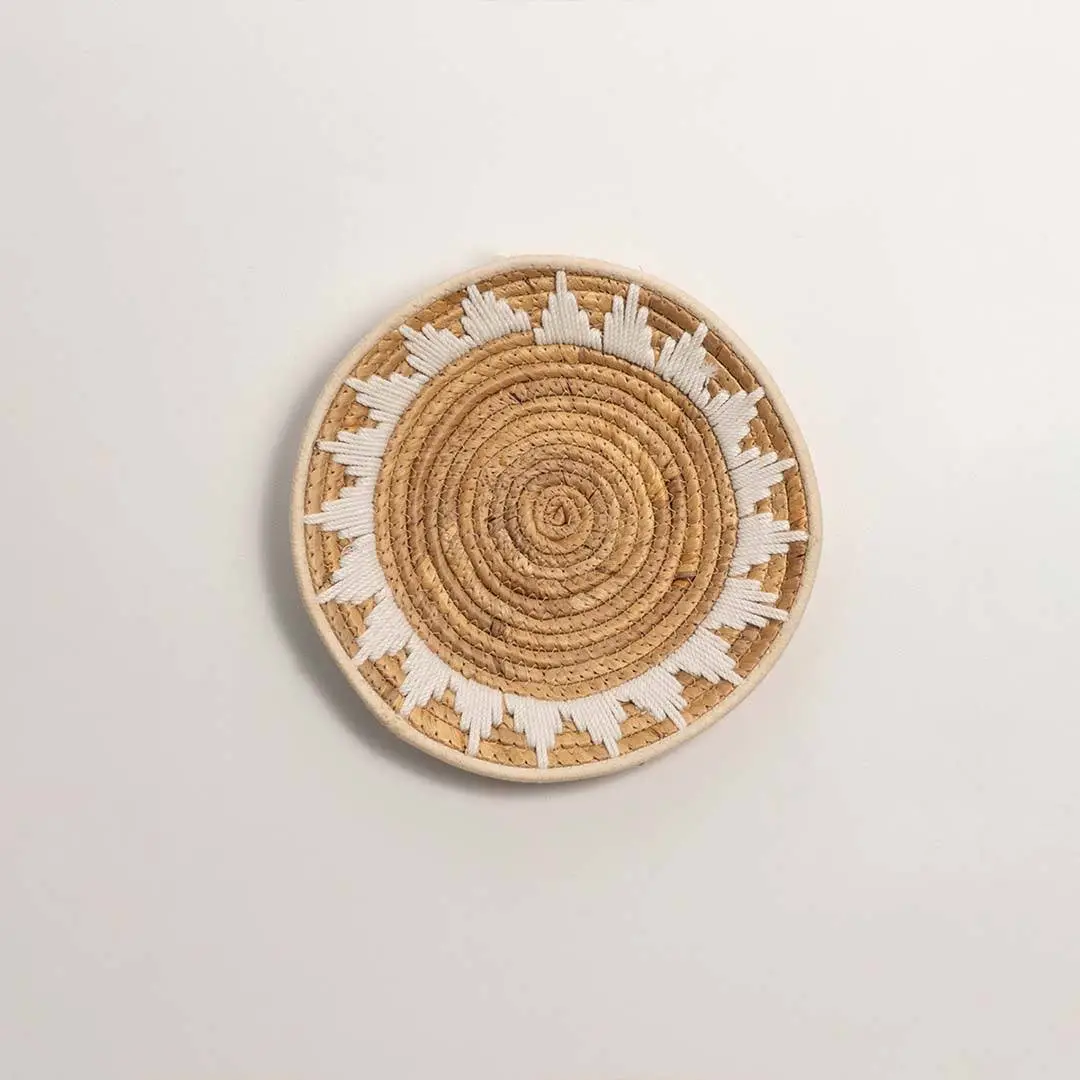 Round handcrafted natural seagrass wall basket with geometric pattern on white background image.