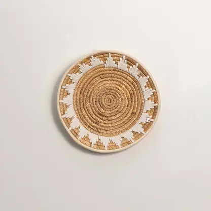 Round handcrafted natural seagrass wall basket with geometric pattern on white background image.