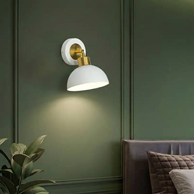 Wall light with white metal shade casting soft glow styled on green wall creating cozy ambient lighting for home decor.