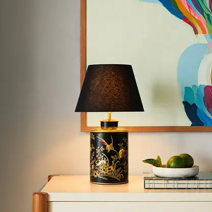 Black floral ceramic table lamp with black fabric shade adding sophisticated ambient lighting to modern console styling.