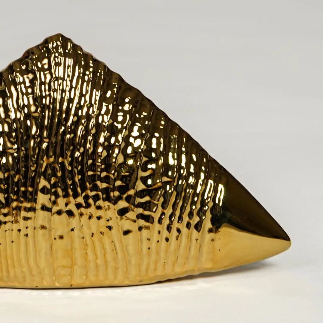 Close view of gold striped ceramic triangle decor featuring glossy metallic finish and ribbed pattern.