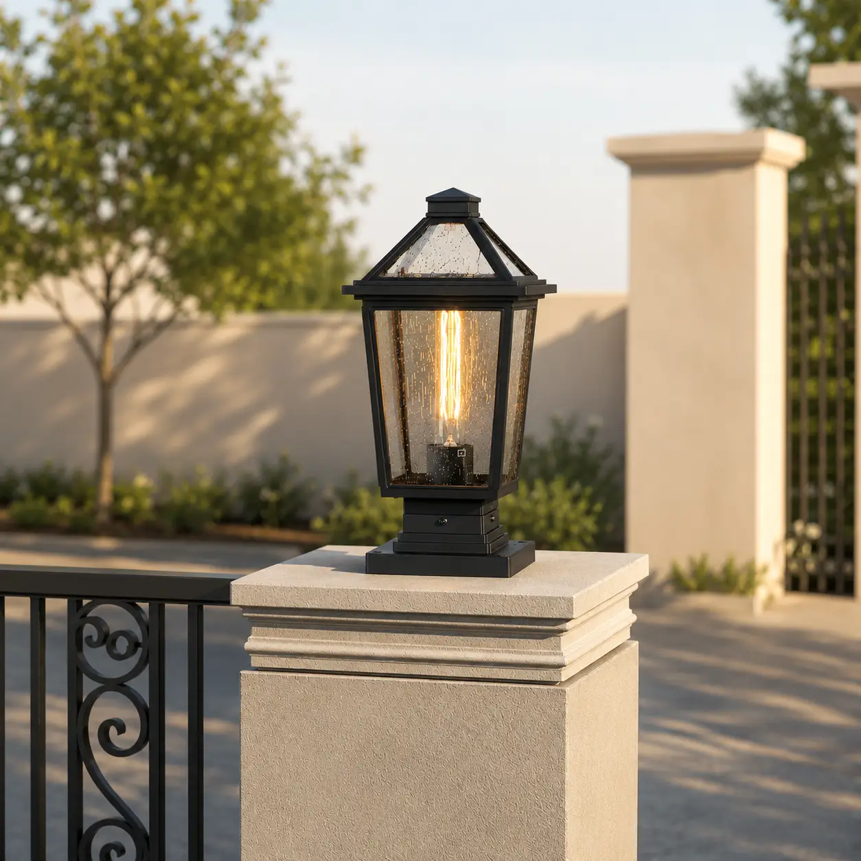 Classic black aluminum tapered clear glass post lantern light on concrete fence pillar for traditional backyard yard path.