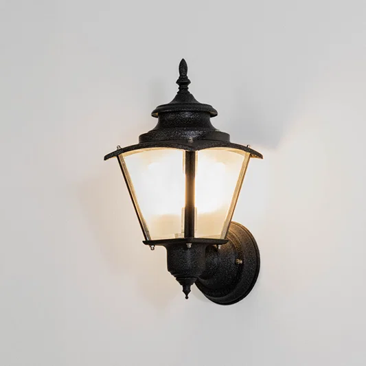 Black metal outdoor wall light on white background with clear glass shade for modern patio lighting decor.