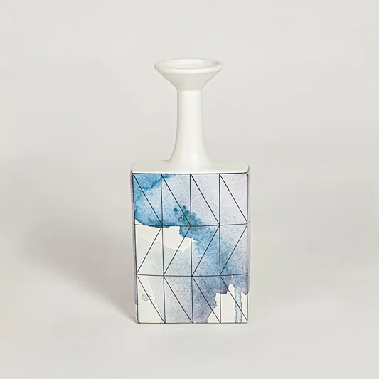 Blue glass bottle vase for modern shelf placement and elegant indoor home decor styling accent piece.
