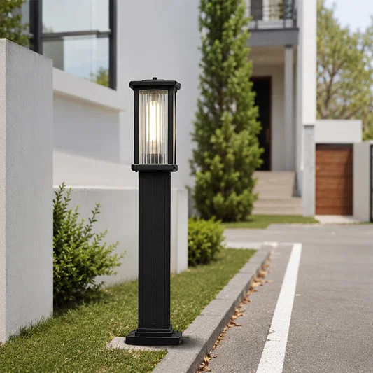 Contemporary black metal rectangular column bollard post light on driveway curb for modern residential estate path decor.